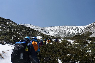 カール下部から山頂へ雪道を進む